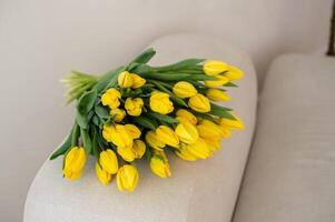 Yellow tulips bouquet on a beige sofa. photo