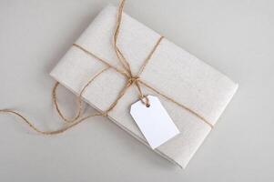 Empty price tag on white fabric, label mockup, gift folded linen fabric with tag on white background photo