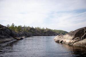 A river flowing in the mountain peaks. The shore is made of stones. Forest on the lake shore photo