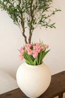 Pink tulips in white vase on wooden table. photo