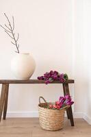 Rustic wooden bench with ceramic vase and woven basket with purple tulips. photo