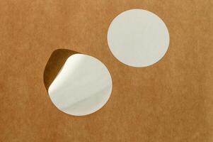 Round white stickers on brown paper background with natural sunlight. photo