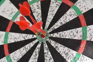 Darts Hitting in the Center of a Dartboard photo