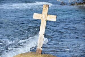 Waves Rolling Ashore Near a Wooden Cross photo