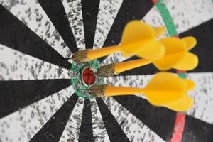 Close Up of Darts Clustered Together in a Dart Board photo