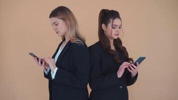 two women in business suits standing next to each other looking at phone video