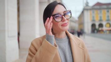 une femme dans une manteau et des lunettes permanent sur une rue video