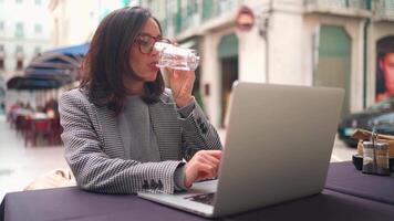 a woman sitting at a table working with a laptop video