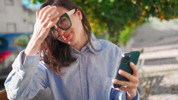 een vrouw in bril gebruik makend van haar telefoon video