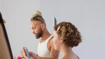 female model looking on her phone while the make up artist is fixing his tools video