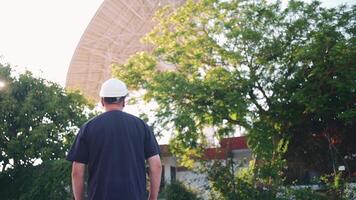 a man in a hard hat walking in front of a satellite video