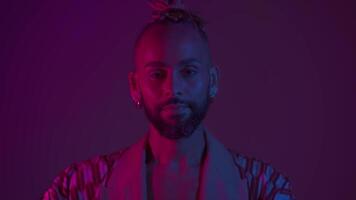 a man with a beard and dreadlocks is standing in front of a purple light video