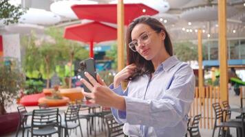 een vrouw in bril nemen een selfie met een smartphone video
