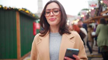 a woman in glasses is holding a cell phone video