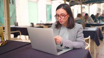 a woman sitting at a table working with a laptop video