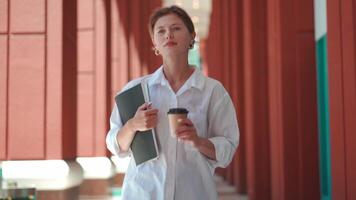 a woman in a white shirt is holding a coffee cup video