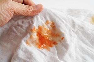 Dirty spicy sauce stain on cloth to wash with washing powder, cleaning housework concept. photo