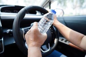 Asian woman driver hold drink in car, dangerous and risk an accident. photo