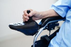 Asian elderly disability woman patient use joystick electric wheelchair in hospital. photo