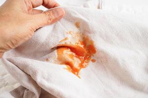 Dirty tomato sauce stain or ketchup on cloth to wash with washing powder, cleaning housework concept. photo