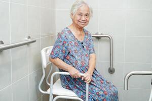 Asian elderly old woman patient use toilet support rail in bathroom, handrail safety grab bar, security in nursing hospital. photo