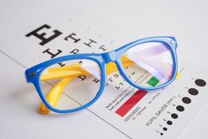 Glasses on eye exam chart to test eyesight accuracy of reading. photo