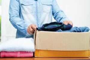 Clothes donations in cardboard box for volunteer. photo