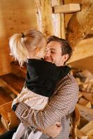 Smiling dad hugs little girl standing on his lap and hugging his neck photo