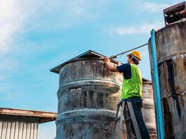 ingeniero que controla la calidad del agua se encuentra en las escaleras de riesgo en lugares altos operando equipos de filtración o purificación de agua industrial viejos tanques de cemento para mantener el agua en la fábrica de agua foto