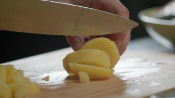 The cook cuts the potatoes into slices using a knife. video