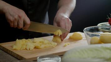 a lindo masculino mãos do a cozinhar cortar batatas para dentro fatias video