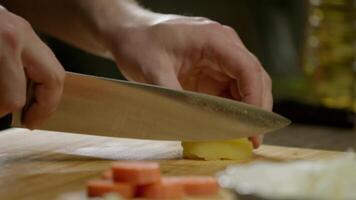 The cook is slicing potatoes on a cutting board in the kitchen of the restaurant. video