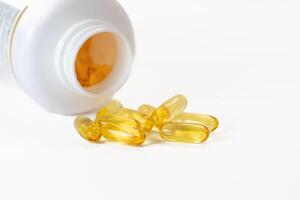 Yellow fish oil capsules in a jelly shell near the white jar photo