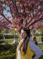 A happy mother and child are walking under the branches of a cherry tree photo