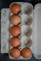 Fresh chicken eggs in a paper tray on the table, selective focus photo