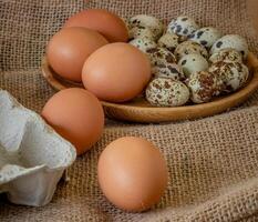 Fresh chicken and quail eggs in tray, plate on wooden board, selective focus photo