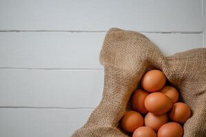 Fresh chicken eggs in a basket on a sack, egg day, wooden table.Selective focus photo