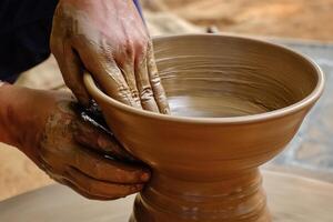 Pottery   skilled wet hands of potter shaping the clay on potter wheel photo