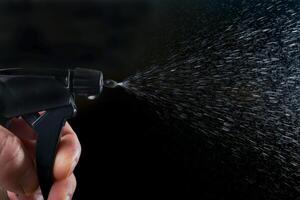 a man's hand pressing the trigger of a sprayer, photo