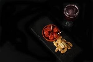 earthenware casserole with fried sausage, bread and a glass of wine photo