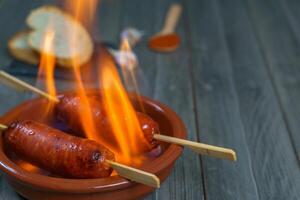 típico Español tapa chorizo en fuego en un loza de barro maceta foto