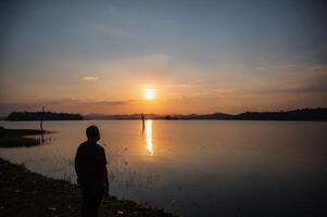 Fat man wearing mask with Sunset view of Pom pee view point.Pom Pee viewpoint is located in Khao Laem National Park, Thong Pha Phum district, Kanchanaburi province photo