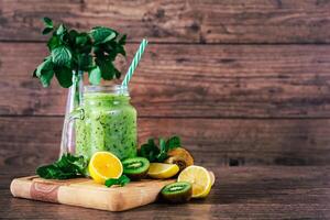 Delicious kiwi smoothie with mint in mason jar on table against dark wooden background. Healthy lifestyle concept photo