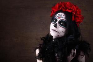 Day of the dead. Halloween. Young woman in day of the dead mask skull face art and rose. Dark background. photo