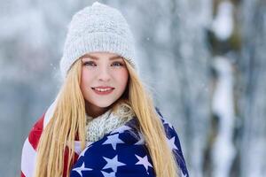 invierno retrato de joven adolescente niña con Estados Unidos bandera. belleza alegre modelo niña riendo y teniendo divertido en invierno parque. hermosa joven mujer al aire libre. disfrutando naturaleza, invierno foto