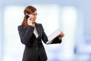 Portrait of a beautiful businesswoman 50 ears old with mobile phone in the office. photo