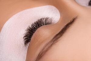 Eyelash Extension Procedure. Close up view of beautiful female eye with long eyelashes, smooth healthy skin. photo