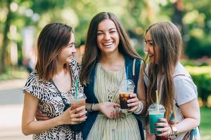 verano estilo de vida retrato multirracial mujer disfrutar bonito día, participación lentes de batidos contento amigos en el parque en un soleado día. mejor amigos muchachas teniendo divertido, alegría. estilo de vida. asiático, judía y foto