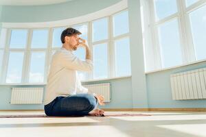 Man practice yoga. Young attractive male doing breathing exercises. Guy meditating at home along during the pandemic. Relaxation and resting concept for isolation. Slide shot. photo