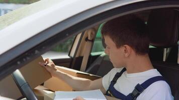 Moving and delivery of manufactured goods. The courier fills in the cargo documents. Many craft boxes are stacked in the passenger seat next to the driver. Delivery of goods home video